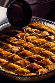 Fresh syrup being poured over diamond-cut baklava
