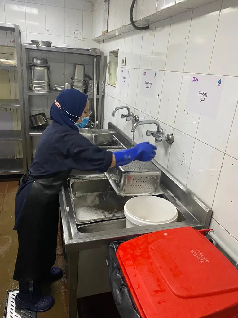 Cloud kitchen team member washing equipment
